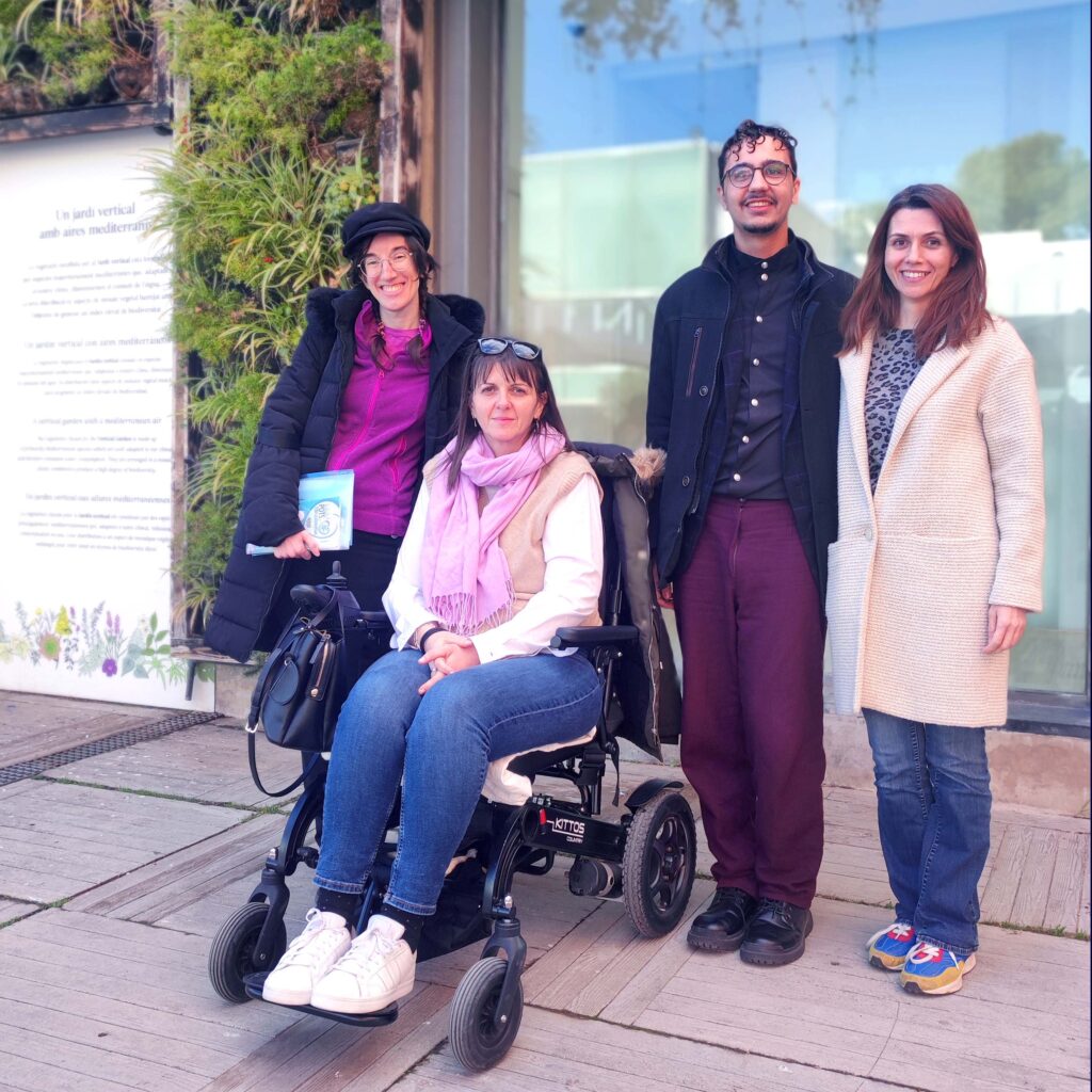 Por qué asociarse Foto de 4 miembros de la Junta Directiva de AEPOD. Las dos Vicepresidentas, una sentada en la silla de ruedas eléctrica. El Secretario y la Secretaria. En una terraza exterior grande de un museo una mañana soleada. El suelo es de madera. Detrás de ellos una pared acristalada con plantas verdes en vertical.
